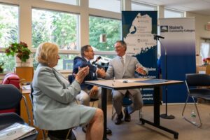 MCCS President David Daigler and UMS Chancellor Dannel Malloy shake hands after signing the Transfer ME agreement, while Governor Janet Mills applauds.